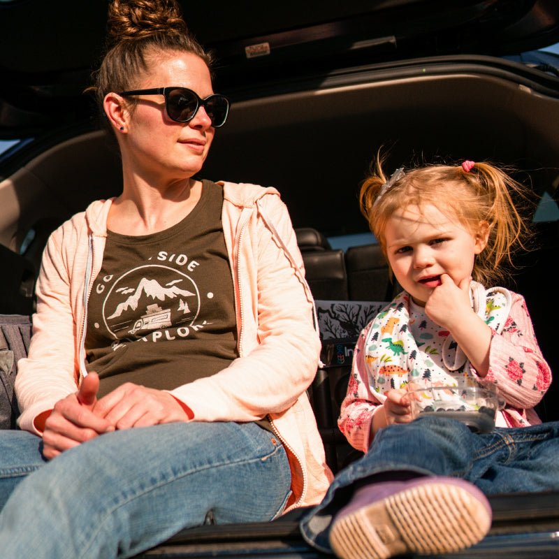 Mom and kid having a snack in the trunk of the car during a road trip