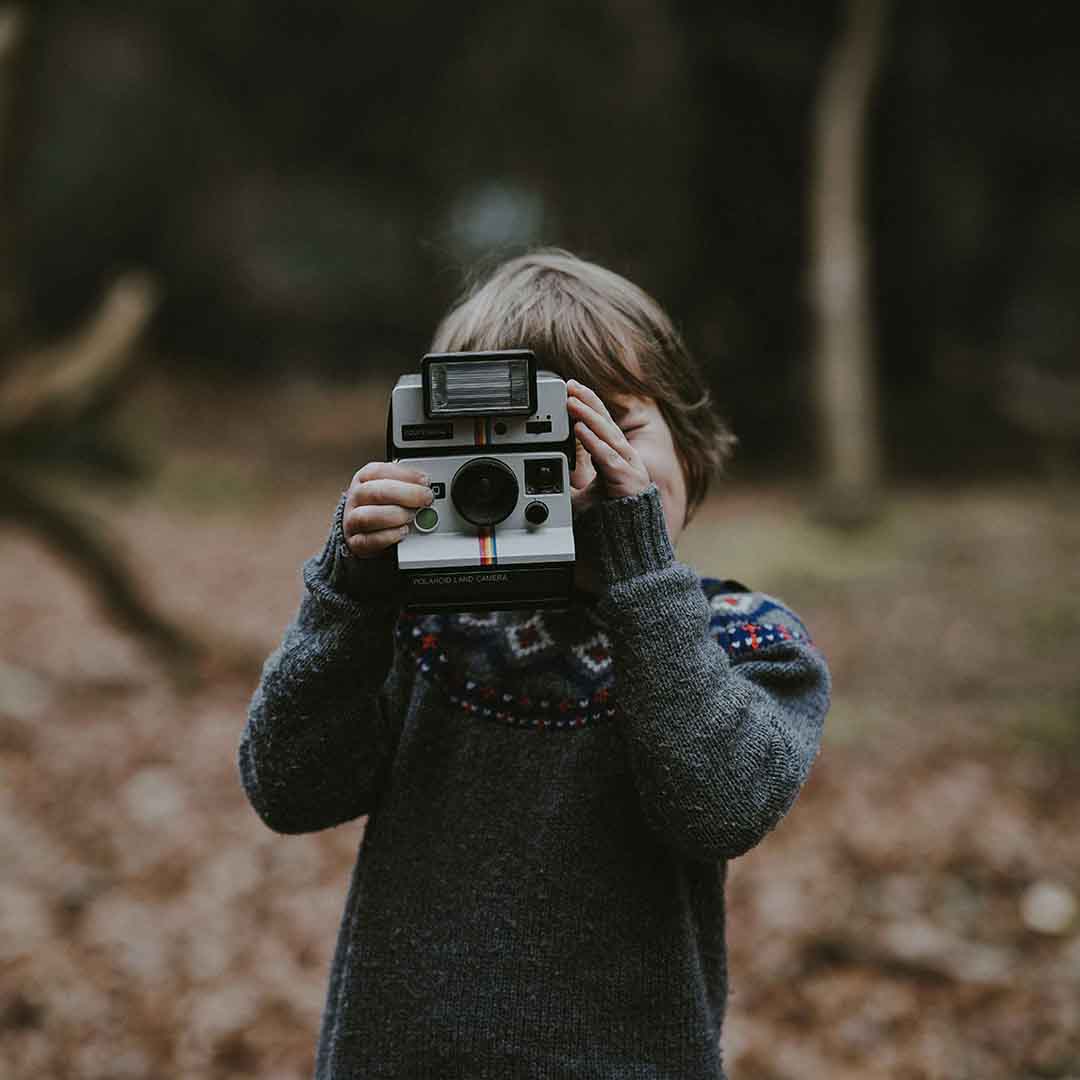 A child exploring nature with a camera, blending technology and outdoor play.