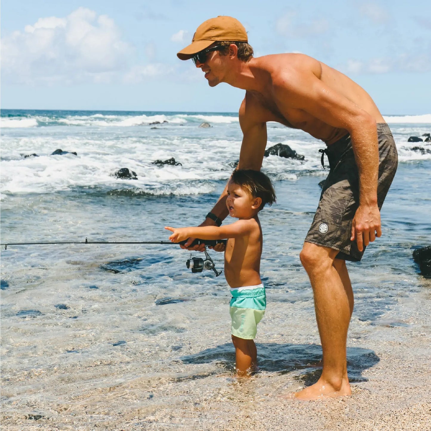 A dad and a young boy fishing in the ocean, symbolizing outdoor family adventures and New Year’s resolutions to connect with nature.