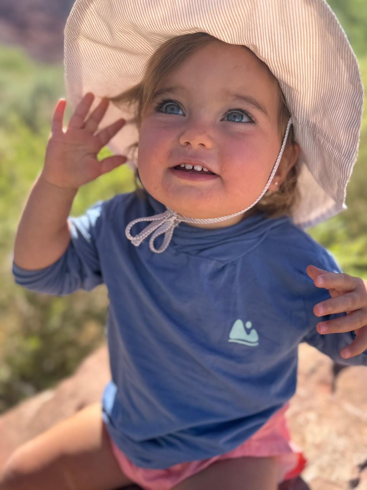 baby girl in blue sun shirt and hat