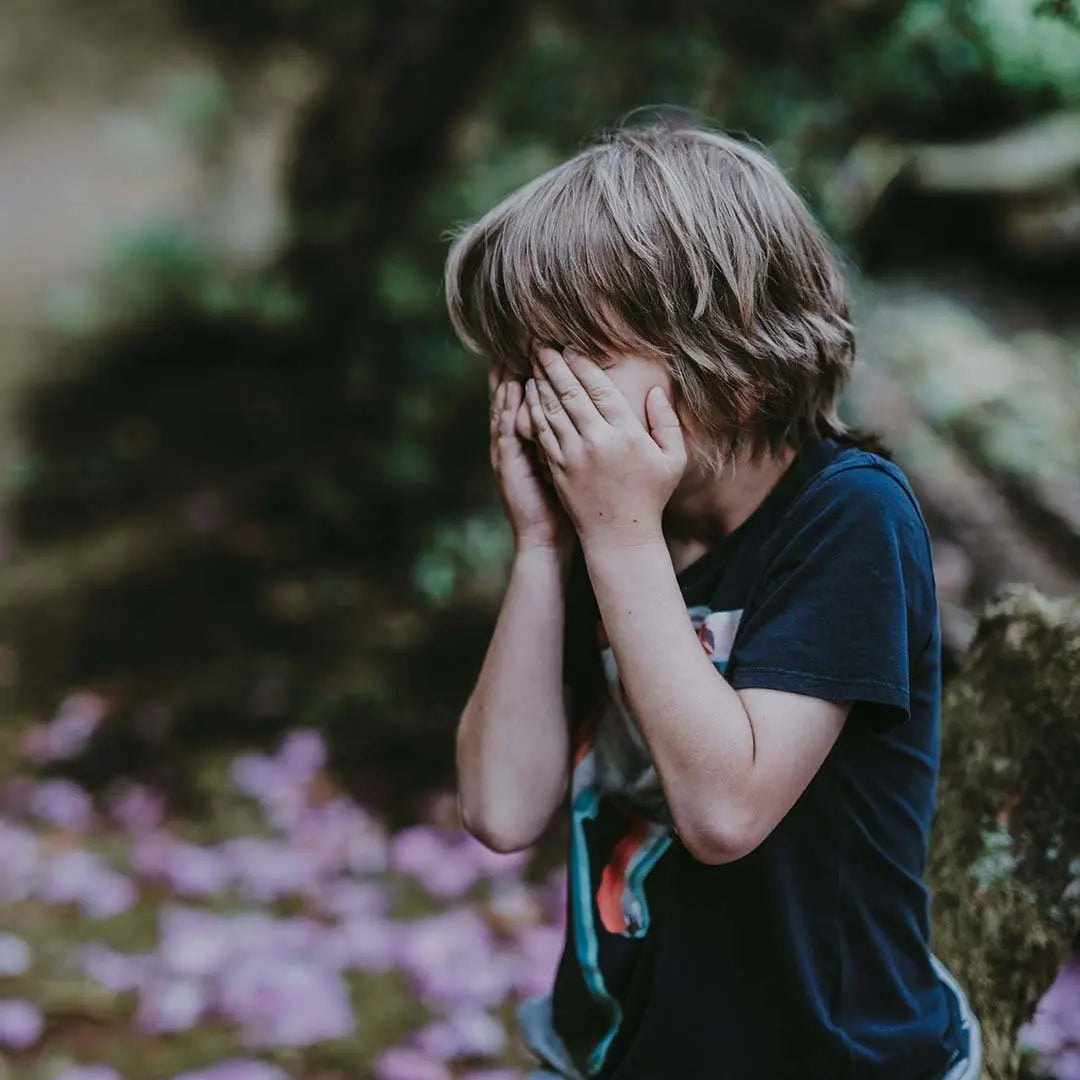 a child in a shaded park after an overstimulating outdoor experience.
