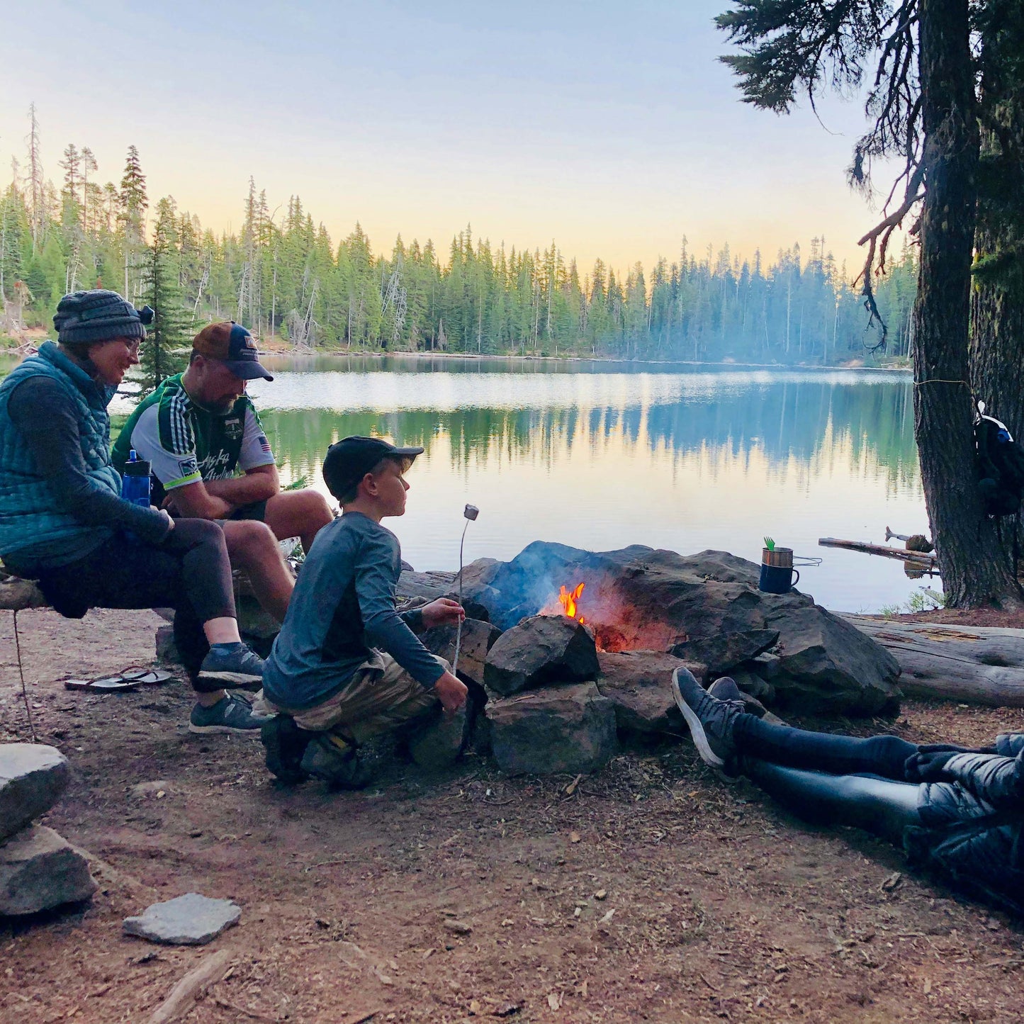 A happy family sitting around a campfire, roasting marshmallows and laughing.