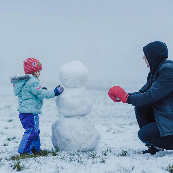 kid playing in snow with parent