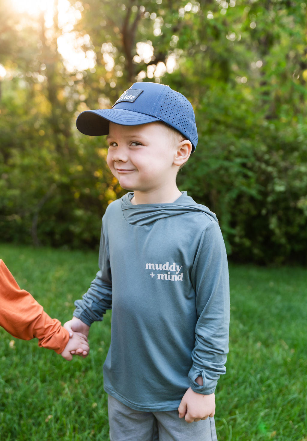 Boy wearing the Muddy + Mind Kids Snapback Hat and The ONE Shirt in Teal, perfect for sun-safe outdoor play.