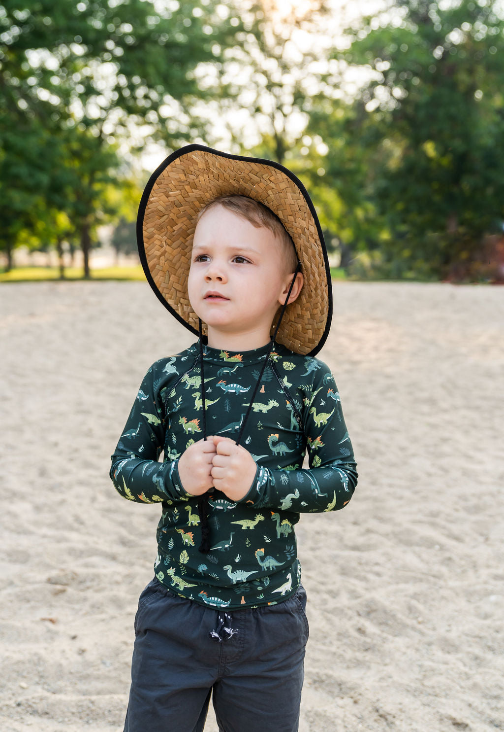 Little boy wearing Muddy + Mind’s Kids Beach Comber Straw Hat and UPF 50+ rash guard, staying sun-safe during a beach adventure.