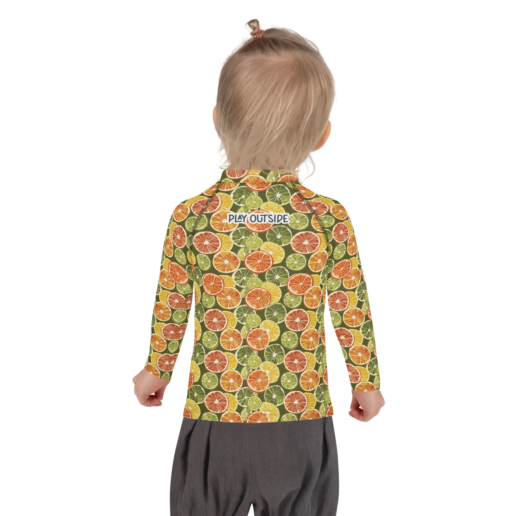 A child wearing a citrus-print rash guard with bright fruit patterns, offering full sun protection, shown from the back.
