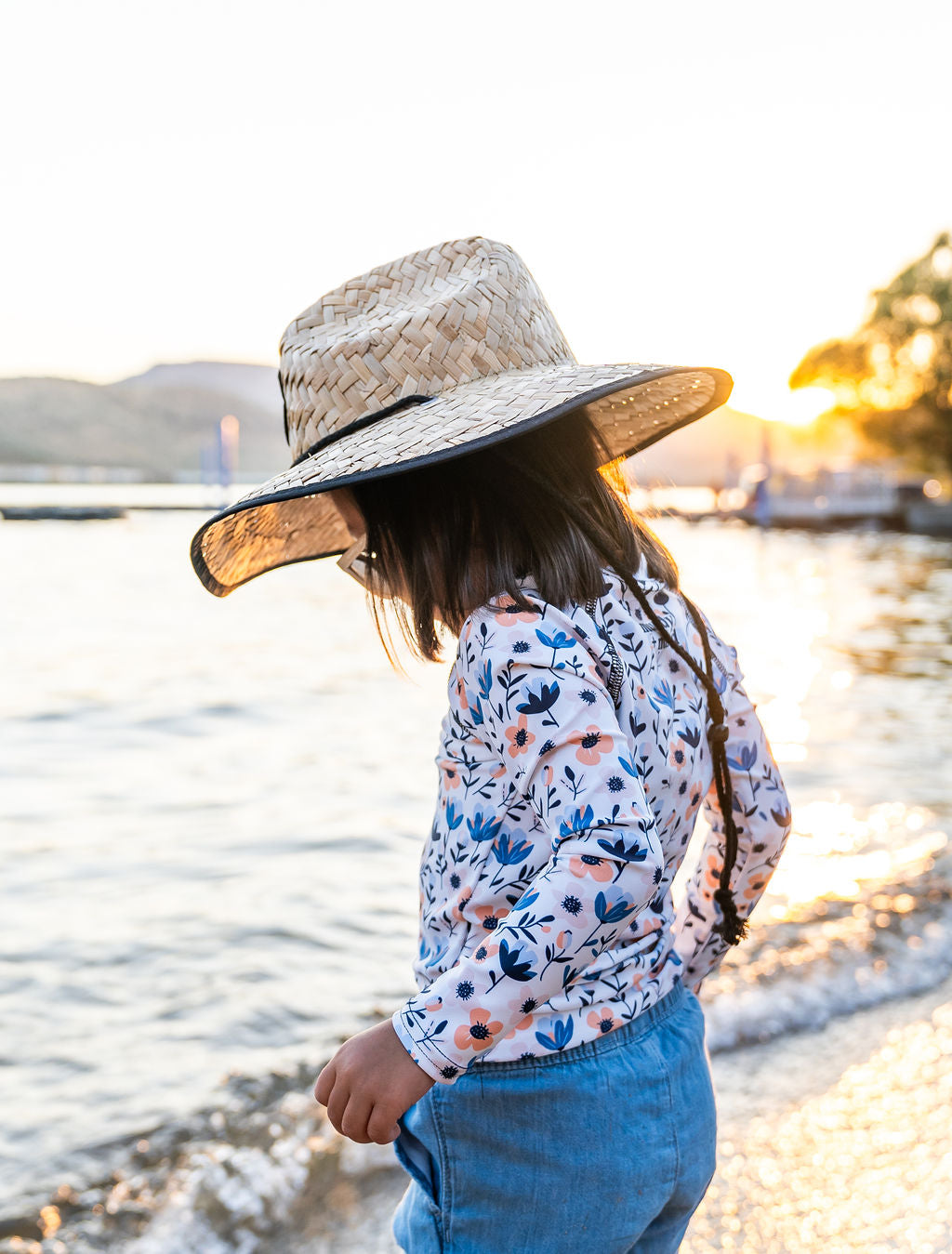 Girl enjoying outdoor play in Muddy + Mind’s straw hat and protective rash guard, offering all-day sun protection and comfort.