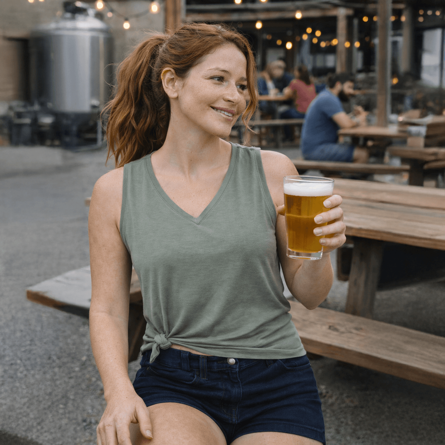 Woman holding a beer at an outdoor brewery.