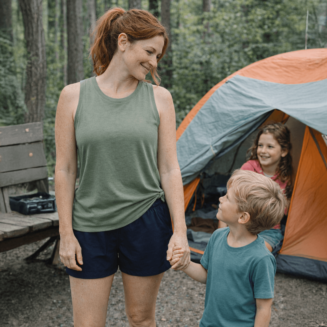 Woman and two children at a campsite with an orange tent in the background