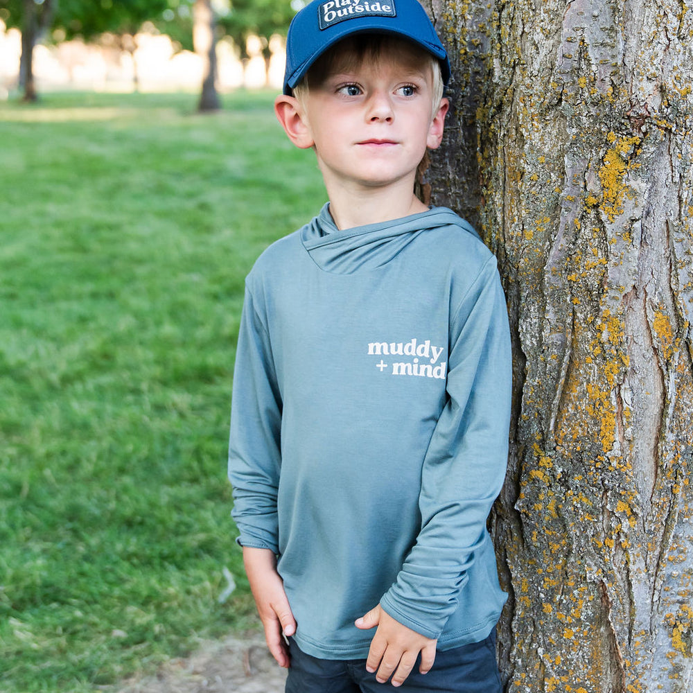 
                      
                        Child wearing The ONE Shirt in Teal, enjoying an outdoor adventure with breathable, all-weather sun-safe comfort. Wearing the play outside snapback
                      
                    