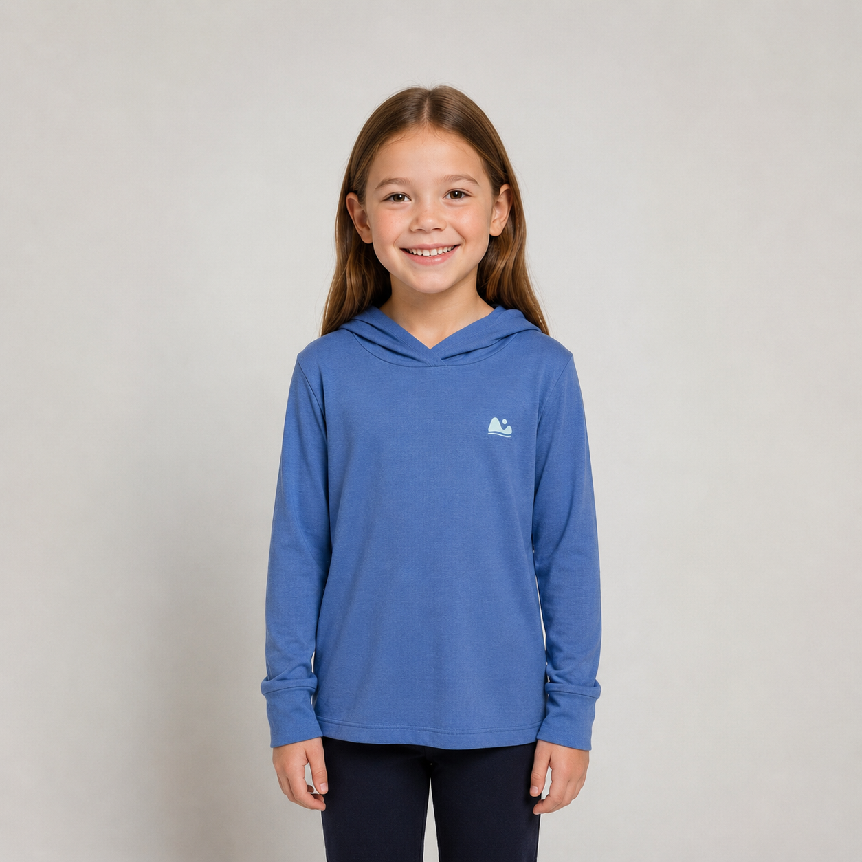 Young girl wearing a blue bamboo sun hoodie with a logo on a plain background
